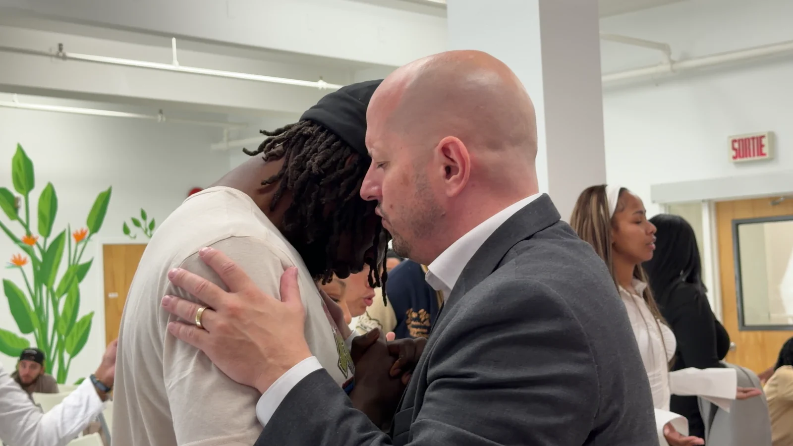 Évangéliste Emanuel Ouellet prie avec un homme, la main posée sur son épaule